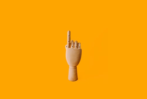 wooden hand pointing up with yellow background